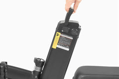 Hand holding a black DYU A5 Upgraded Folding Electric Bike battery pack with visible branding on a white background