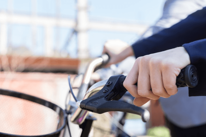 Close-up of a person gripping an electric bike handlebar outdoors from Pogo Cycles