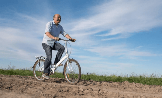 Senior man riding electric bike outdoors on dirt path, promoting Pogo Cycles e-bikes